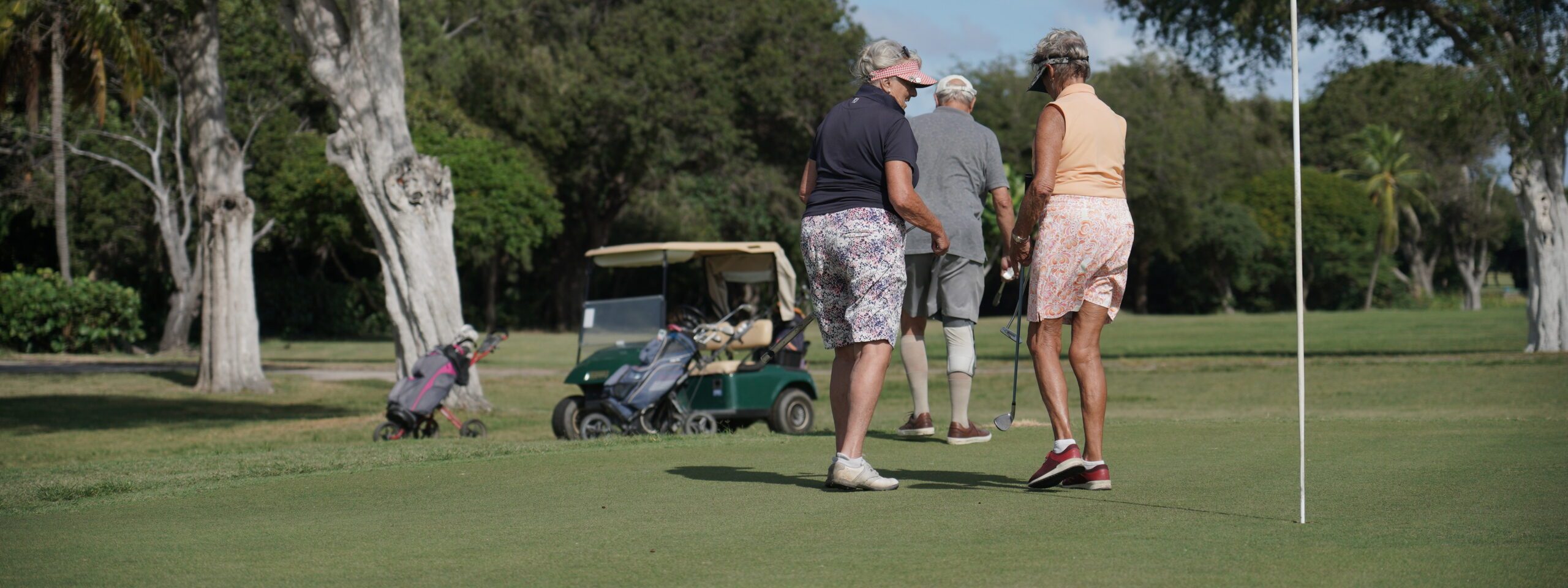Golfers on the green with a golf cart behind them